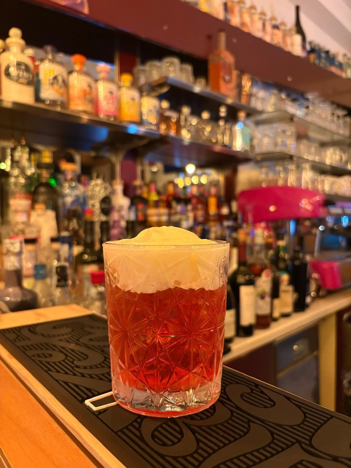 Cocktail rosso con schiuma al bancone del bar